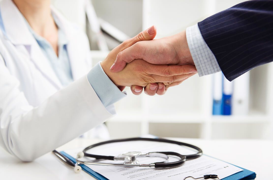 Woman doctor shaking hand with businessman in the office