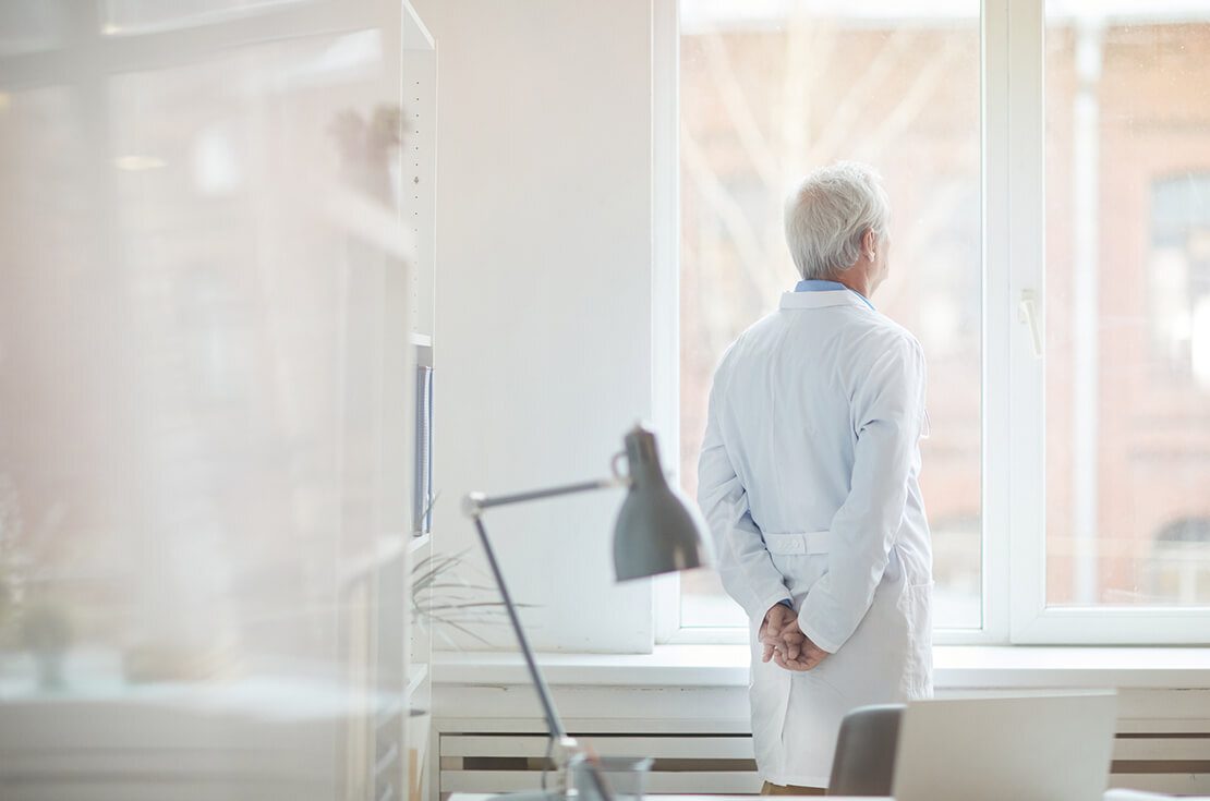 Male senior doctor standing at office